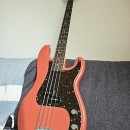 Elektrická basová kytara s růžovým trupem a hnědým hmatníkem. Nástroj má tmavě hnědý pickguard s leopardím vzorem a čtyři struny. Na hlavě krku je vi…