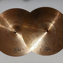 Dva mosazné činely v barvě zlata. Na levém je nápis HI-HAT TOP 13" a logo MAGIC BRONZE. Na pravém je nápis HI-HAT BOTTOM 13" a logo MAGIC BRONZE. Pov…