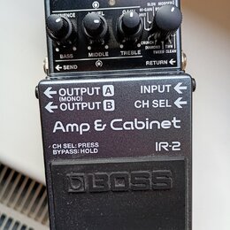 Černý efekt pedál značky BOSS s nápisem Amp & Cabinet a označením modelu IR-2. Horní část obsahuje čtyři ovládací knoflíky a nápisy CHECK, BASS, MIDD…