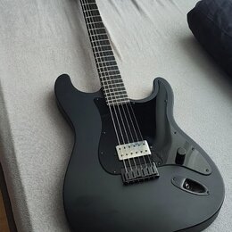 Černá elektrická kytara s matným povrchem a černým pickguardem. Na hlavě hmatníku je viditelné logo Fender. Nástroj má jeden humbucker v pozici kobyl…