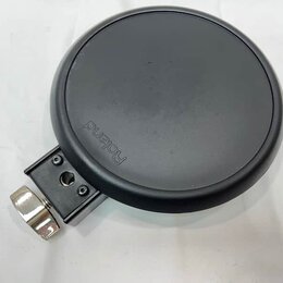 Černý kruhový elektronický pad s nápisem Roland. Pad je vybaven kovovým přichycovadlem s utahovacím šroubem. Povrch padu vykazuje mírné známky opotře…