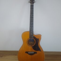Akustická kytara s vyřezem v korpusu, přirozenou dřevěnou barvou a tmavým hmatníkem. Na hlavě je bílý nápis YAMAHA a uvnitř ozvukové otvory je vidite…