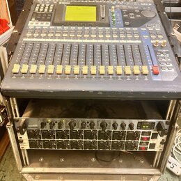 Digitální mixážní pult značky YAMAHA, model OXY 5, umístěný v transportním case. Zařízení má šedé tělo s modrými prvky, LCD displej a řadu posuvníků.…