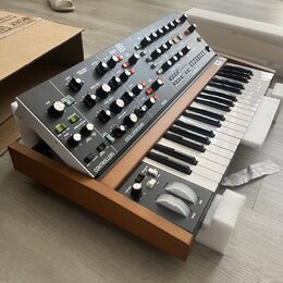 Elektronický syntetizátor v dřevěném korpusu s černým ovládacím panelem a klaviaturou. Na panelu je nápis POLY 8 a sekce označené jako OSCILLATOR BAN…