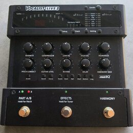 Černý procesor vokálních efektů s nápisem VOCALIST LIVE 3. Zařízení obsahuje několik otočných potenciometrů s popisky WARMTH, COMPRESSOR, LOW EQ, HIG…