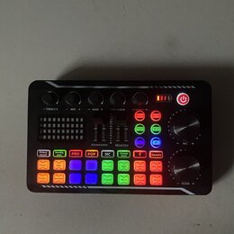 Černý zvukový mixér s řadou barevných tlačítek a ovládacích prvků. Na horní části jsou čtyři černé otočné knoflíky s popisky -TREBLE+, -MID +, -BASS…