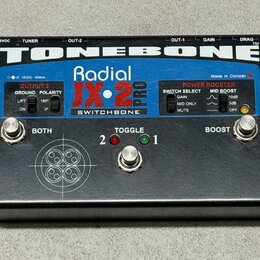Černý efekt pedál s nápisy TONEBONE, Radial JX-2 PRO a SWITCHBONE. Na horní straně jsou ovládací prvky: dva stisknuté přepínače s popisky BOTH a BOOS…
