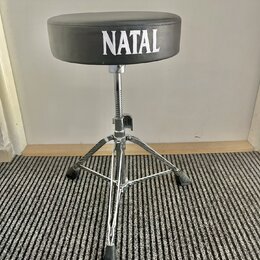 Černý bubeníckýstolek s kulatým polstrovaným sedadlem. Na přední straně sedadla je bílý nápis NATAL. Nohy a středový sloupek jsou vyrobeny z chromova…