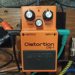 Oranžový efekt pedál s černým spínacím tlačítkem. Na zařízení jsou nápisy Distortion, DS-1 a logo BOSS. Pedál má tři stříbrné oválné knoflíky s popis…