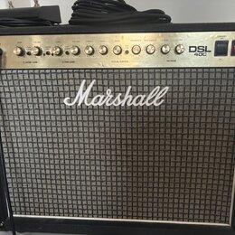 Kytarový kombozesilovač značky Marshall s modelem DSL 40C. Má černý kryt, stříbrný ovládací panel s řadou knoflíků a šedý textilní přední grill. Na p…