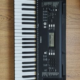 Černý digitální klavír s bílými a černými klávesami. Na korpusu je vlevo nápis PSR-E323 a uprostřed logo YAMAHA. Nástroj obsahuje ovládací panel s di…