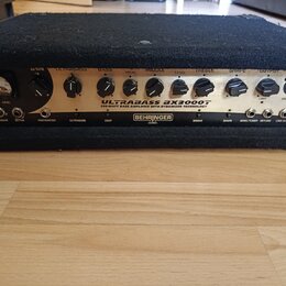 Černý basový zesilovač s kovovým předním panelem. Na panelu je nápis BEHRINGER a model ULTRABASS BX3000T s doplňujícím textem 300-WATT BASS AMPLIFIER…