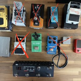 Fotografie zobrazuje sadu kytarových efektů a příslušenství na dřevěném povrchu. V horní řadě jsou pedály Graphic Equalizer EQ700, TONEX a Boss Chrom…