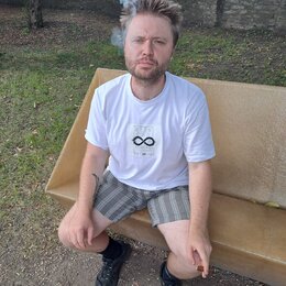 Na fotografii není žádný hudební nástroj ani příslušenství. Je zde zobrazen muž sedící na betonové lavičce v parku.