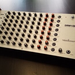 Stříbrný analogový drum synthesizer s dřevěnými bočními panely. Na pravé straně je uveden název modelu DRM1 MK III a značka VERMONA. Přístroj obsahuj…