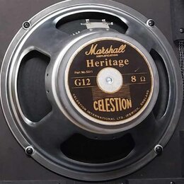 Fotografie znázorňuje reproduktor v kovovém rámu. Na středovém štítku jsou nápisy Marshall AMPLIFICATION, Heritage, Part No.S311, G12, 8 Ω a CELESTIO…
