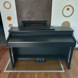 Černý digitální piano v kompaktním provedení s integrovaným stojanem. Nástroj má matný povrch a v dolní části jsou umístěny tři pedály. Na viditelnýc…