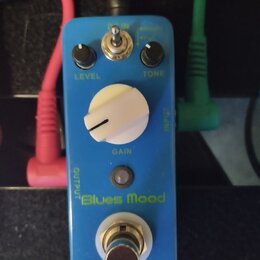 Modrý kytarový efekt s nápisem Blues Mood. Na horní části jsou dva černé otočné knoflíky s popisky LEVEL a TONE, přepínač a velký bílý knoflík s popi…