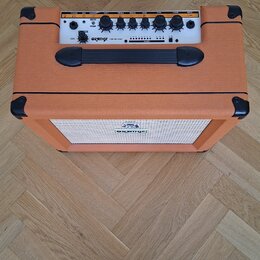 Kytarový kombozesilovač v oranžovém vinylu s černými plastovými rohy a úchytem. Na horním ovládacím panelu je bílý nápis ORANGE CRUSH 20 a řada ovlád…