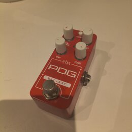Červený efekt pedál s bílými ovládacími knoflíky. Na horní straně jsou nápisy ehx, POG a NYC • DSP, dále popisky DRY, SUB OCTAVE, TONE a FILTER. Povr…