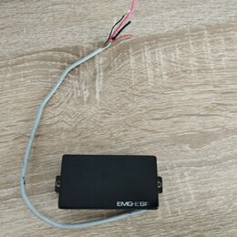 Černý elektrický snímač s obdélníkovým tvarem a dvěma montážními šrouby po stranách. Na spodní hraně je bílý nápis EMG-ESP. Ze snímače vede šedý kabe…