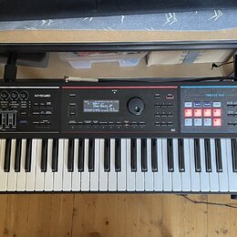 Černý digitální klavír s bílými a černými klávesami. Na pravé straně je nápis Roland JUNO-DS a modrá sekce s označením PHRASE PAD. V horní části jsou…