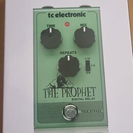 Fotografie znázorňuje krabici s efekt pedálem tc electronic THE PROPHET DIGITAL DELAY. Pedál je zelený, má tři černé ovládací knoflíky s popisky TIME…