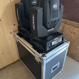 Dvě černé svítidla typu Beam umístěná na černém transportním kufru s hliníkovými hranami a kovovým kováním. Na horní části obou svítil i na jejich bo…