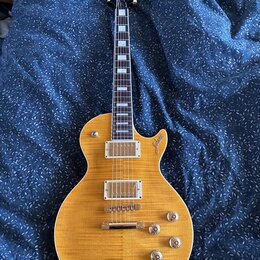 Elektrická kytara s žlutým průsvitným lakem a viditnou strukturou dřeva. Na těle je v oblasti horního výřezu nápis "Custom". Kytara má dva humbuckery…