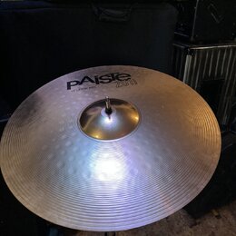 Stříbrný cymbál s koncentrickým žebrováním, umístěný na kovovém stojanu. Na povrchu je černý nápis PAiste 2008 bronze a pod ním text 18" CRASH RIDE.…