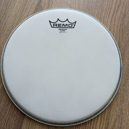 Kruhová bílá naleštěná bubnová blana s matným povrchem. V horní části je černé logo REMO pod stylizovanou korunou a nápisy EMPEROR COATED, MADE IN U.…