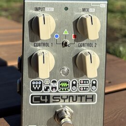 Kovový efekt pedál stříbrné barvy s nápisem C4 SYNTH a logem SOURCE AUDIO v dolní části. Zařízení má čtyři krémové ovládací knoflíky s popisky INPUT…