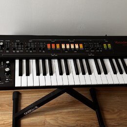 Červený vocoder značky behringer, model Vocoder VC340, s klaviaturní klávesou. Horní panel obsahuje řadu ovládacích knofíků, posuvníků a podsvícených…