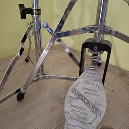Detailní pohled na chromovaný basový pedál. Na šlapadle je vyražen nápis SLINGERLAND CHICAGO USA. Na horní části stojanu je viditelný štítek s nápise…