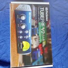 Fotografie znázorňuje krabici s produktem PreSonus TubePre V2. Na obalu je zobrazen modrý jednokanalový předzesilovač s ovládacími prvky Drive, Gain…