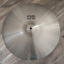 Kruhový kovový činel s kovaným povrchem a viditelnými důlky. Na horní části je černý nápis pAiste GIANT BEAT. Povrch vykazuje mírné známky používání…