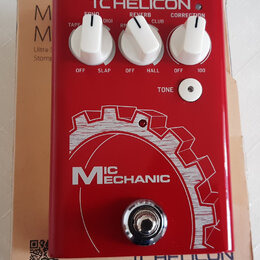 Červený efekt pedál s bílými nápisy a třemi bílými otočnými ovladači. Na horní části je logo TC HELICON a popisky MIC, OUT, POWER, ECHO, REVERB, CORR…