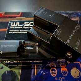 Černý bezdrátový systém WL-50 Wireless System značky BOSS, který se skládá z přijímače a vysílače. Na přijímači jsou nápisy BOSS, Wireless System WL-…
