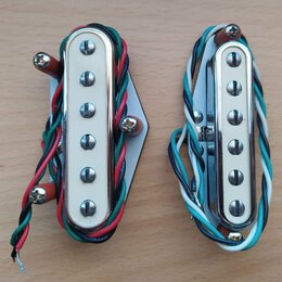 Dvě elektrické snímače typu humbucker s chromovaným krytem a bílými plastovými rámečky. Levý snímač je připevněn na bílou plastovou základnu a má bar…