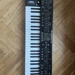 Černý syntetizátor s klávesnicí a dřevěnými bočními panely. Na přístroji je bílý nápis DeepMind 12 a logo Behringer. Ovládací panel obsahuje zahlreic…