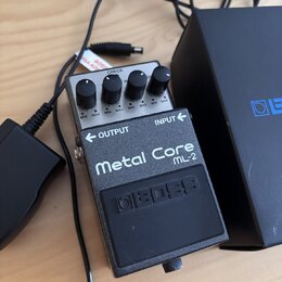 Kytarový efekt pedál stříbrné a černé barvy. Na horní části je nápis Metal Core ML-2 a logo boss. Pedál má čtyři ovládací knoflíky s popisky MIN a MA…