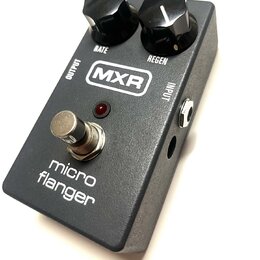 Šedý efekt pedál s nápisem micro flanger a logem MXR. Na horní straně jsou dva černé ovládací knoflíky s popisky RATE a REGEN. V dolní části je umíst…