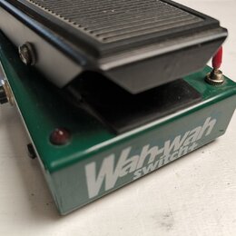 Zelený wah-wah pedál s černým stupněm. Na boku je bílý nápis Wah-wah switch+. Povrch pedálu vykazuje drobné oděrky a znečištění.