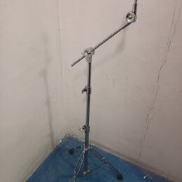 Stříbrný kovový mikrofonní stojan s trojnožkou a výsuvným ramenem. Na horním konci je umístěn černý držák mikrofonu. Povrch stojanu vykazuje známky b…