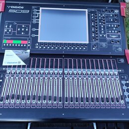 Černý digitální mixovací pult s červenými ochrannými rohy. V horní části je nápis DiGiCo a model SD9, uprostřed velký displej a v dolní části řady po…