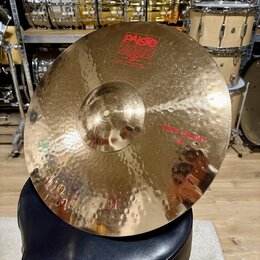 Zlatý kovový činel s kladivovaným povrchem, umístěný na černém polstrovaném sedadle. Na povrchu je červené logo PAiste 2002 s nápisy GRADE 3 ALLOY a…