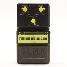 Černý kytarový pedál s nápisem NOISE REDUCER a označením modelu NR-100. Na horní části jsou tři žluté oválné ovladače s popisky THRESHOLD, DECAY a RE…