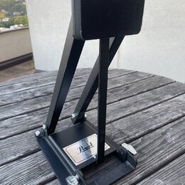 Černý kovový pedál s černou ploščkou. Na spodní základně je viditelné logo Pearl. Předmět vykazuje mírné známky opotřebení povrchu a prach.