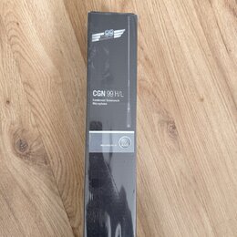 Fotografie znázorňuje úzký černý kartonový obal s produktem uvnitř. Na obalu je bílý nápis CGN 99 H/L a text Condenser Gooseneck Microphone. Ve spodn…