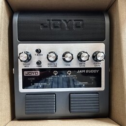 Kompaktní kytarový zesilovač v černé barvě s předním panelem z broušeného kovu. Na mřížce reproduktoru je vyražen nápis JOYO a na ovládacím panelu js…